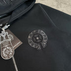 Black hoodie close-up of embroidered circular emblem on the chest