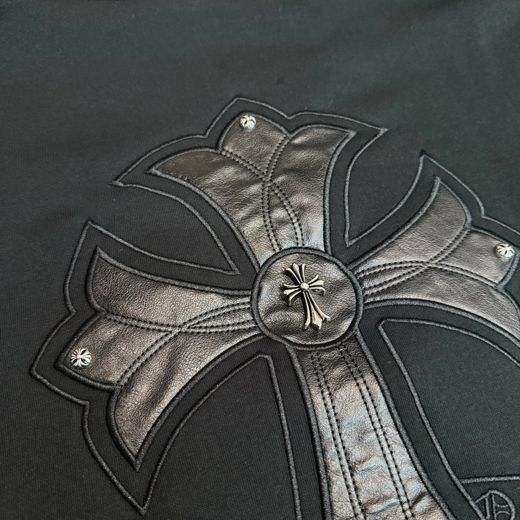 Black hoodie close-up of metallic bow center button and stitched cross details