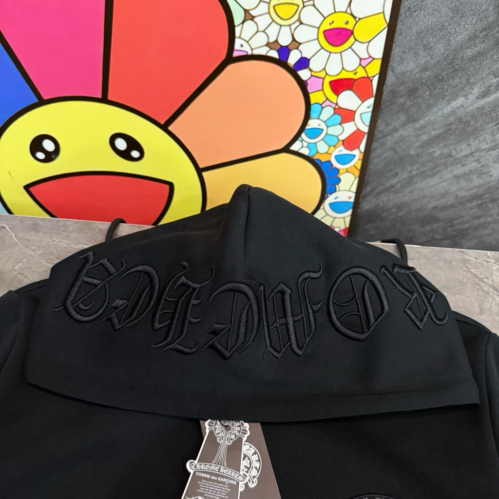 Black hoodie close-up of raised embroidered script graphic across the front