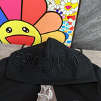 Black hoodie close-up of raised embroidered script graphic across the front