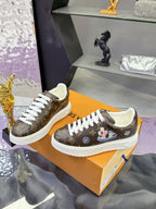 Louis Vuitton monogram sneakers with white laces and side charm detail.