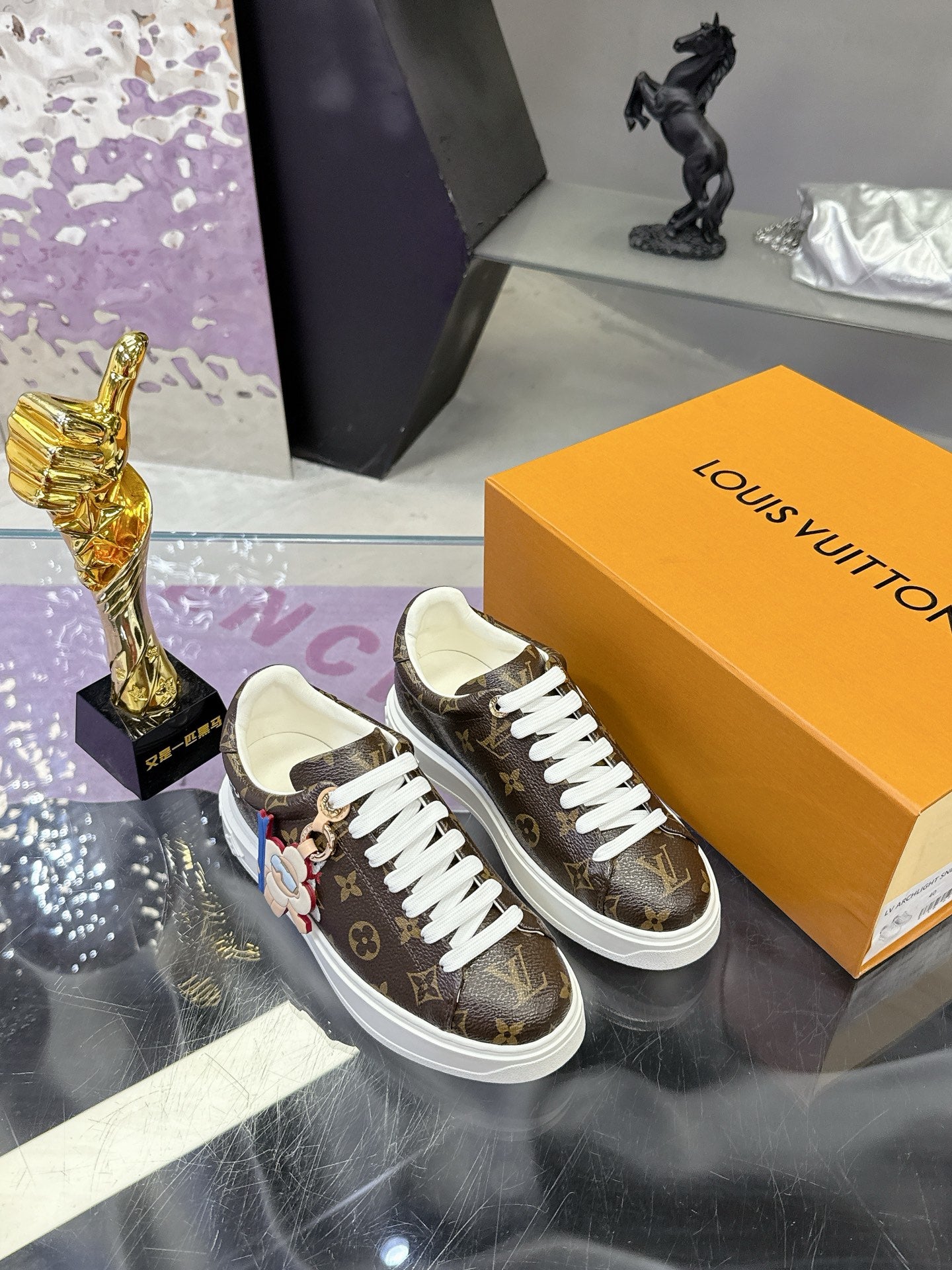 Louis Vuitton monogram sneakers with white laces and colorful charm accents.