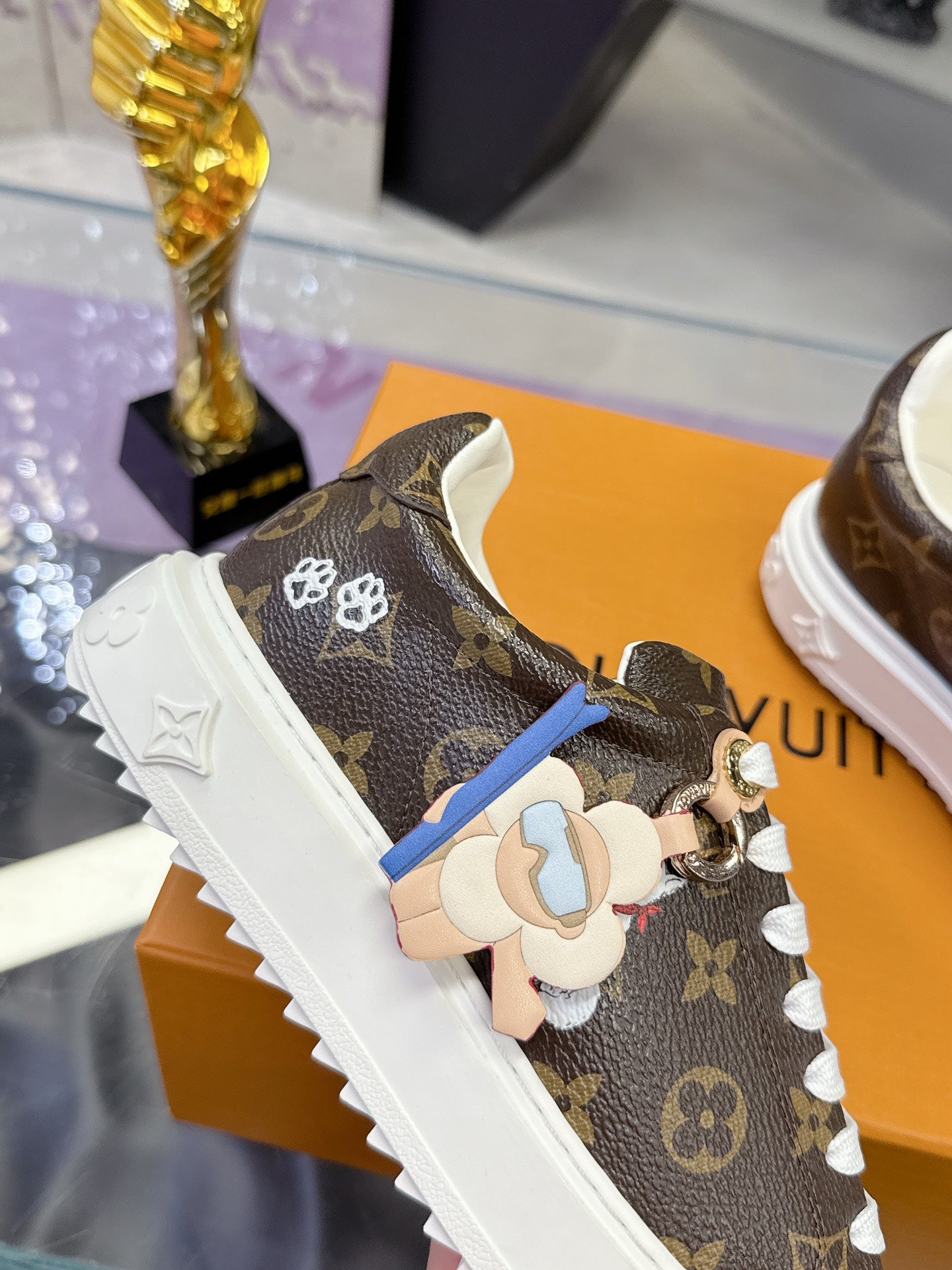 Louis Vuitton monogram sneaker with dangling charm, white sole, white laces.