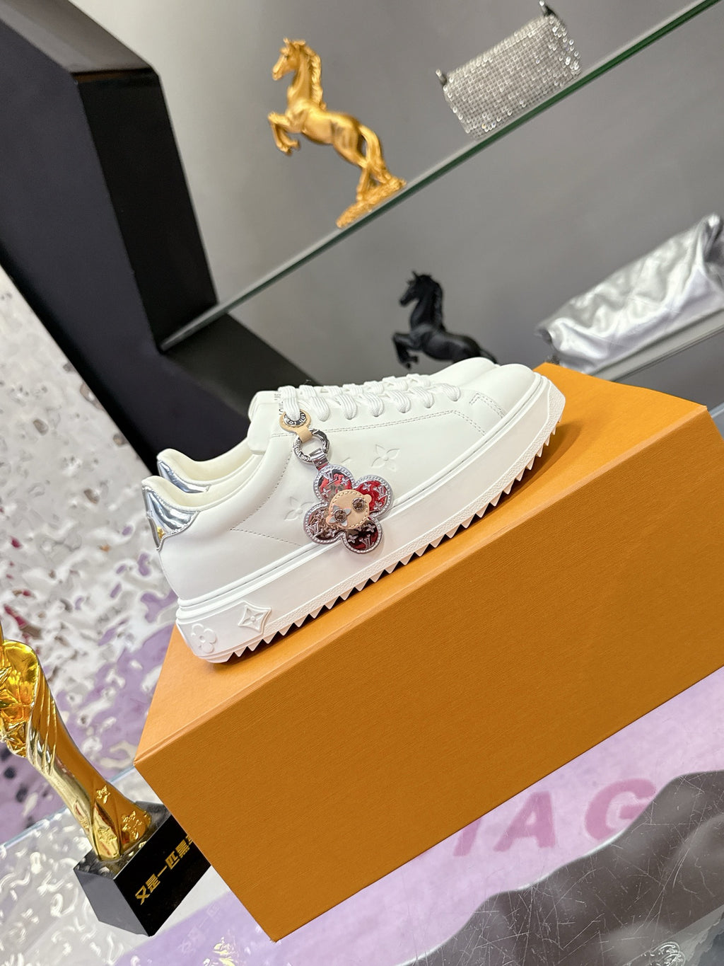 White Louis Vuitton lace-up sneakers with decorative charm on the side