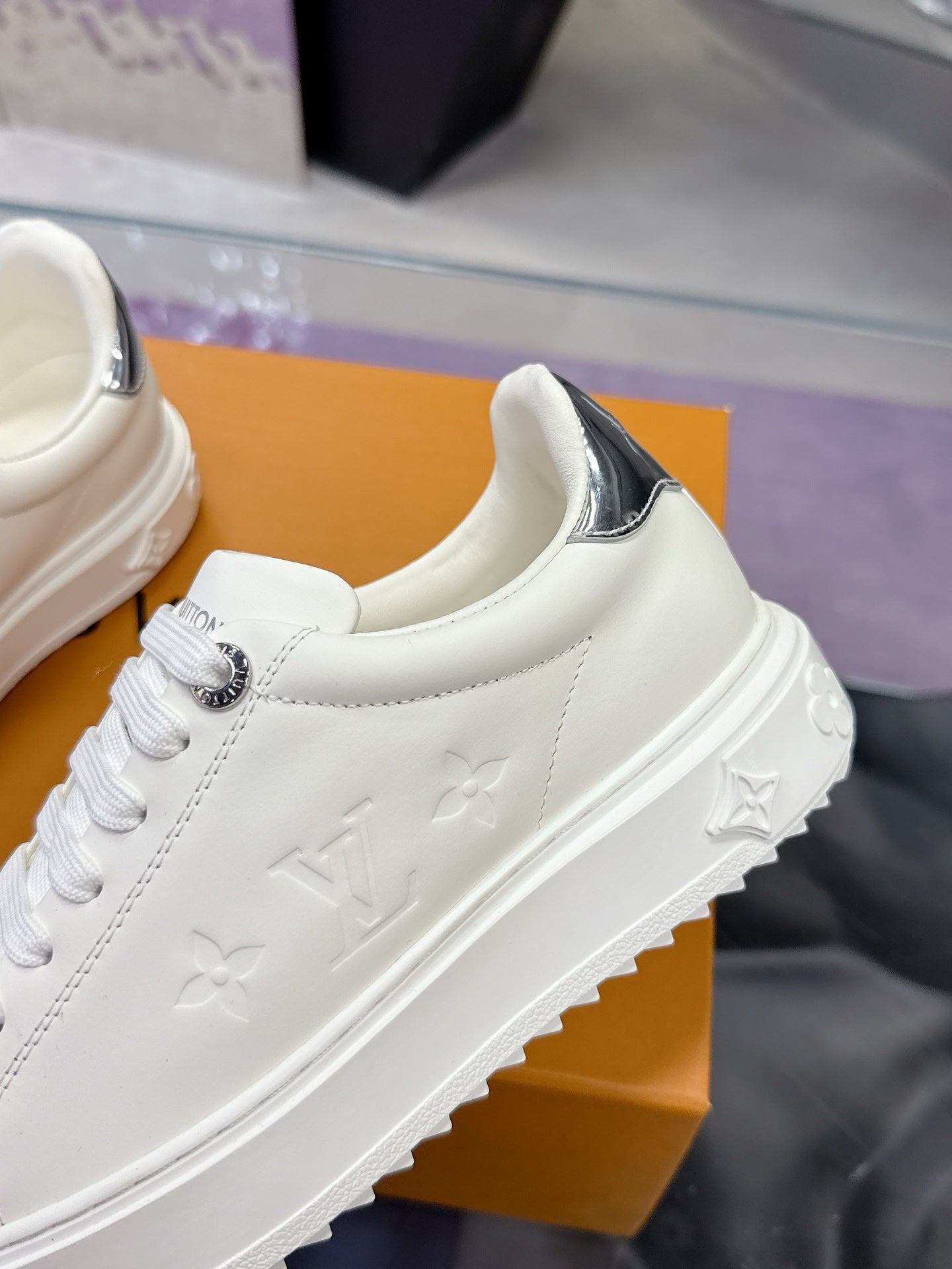 White Louis Vuitton sneaker with embossed monogram pattern on side and silver trim