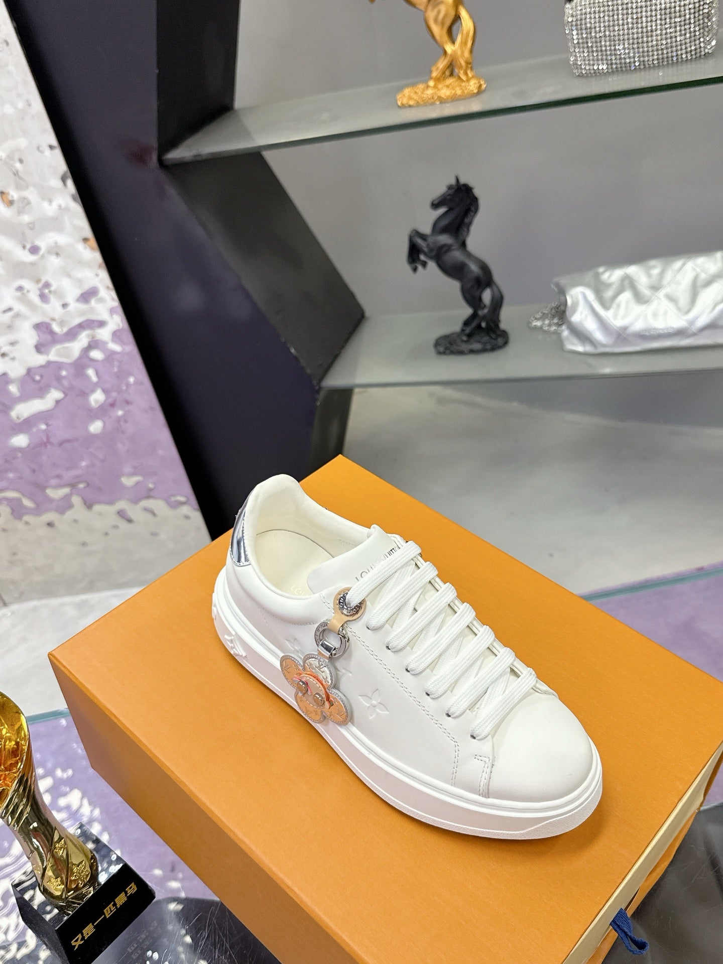 White Louis Vuitton sneakers with lace-up front and charm detail on the side