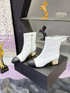 Pair of white mid-calf boots with black toe caps and gold jeweled block heels