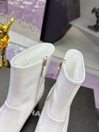 Pair of white mid-calf boots with gold zip pulls and smooth leather finish