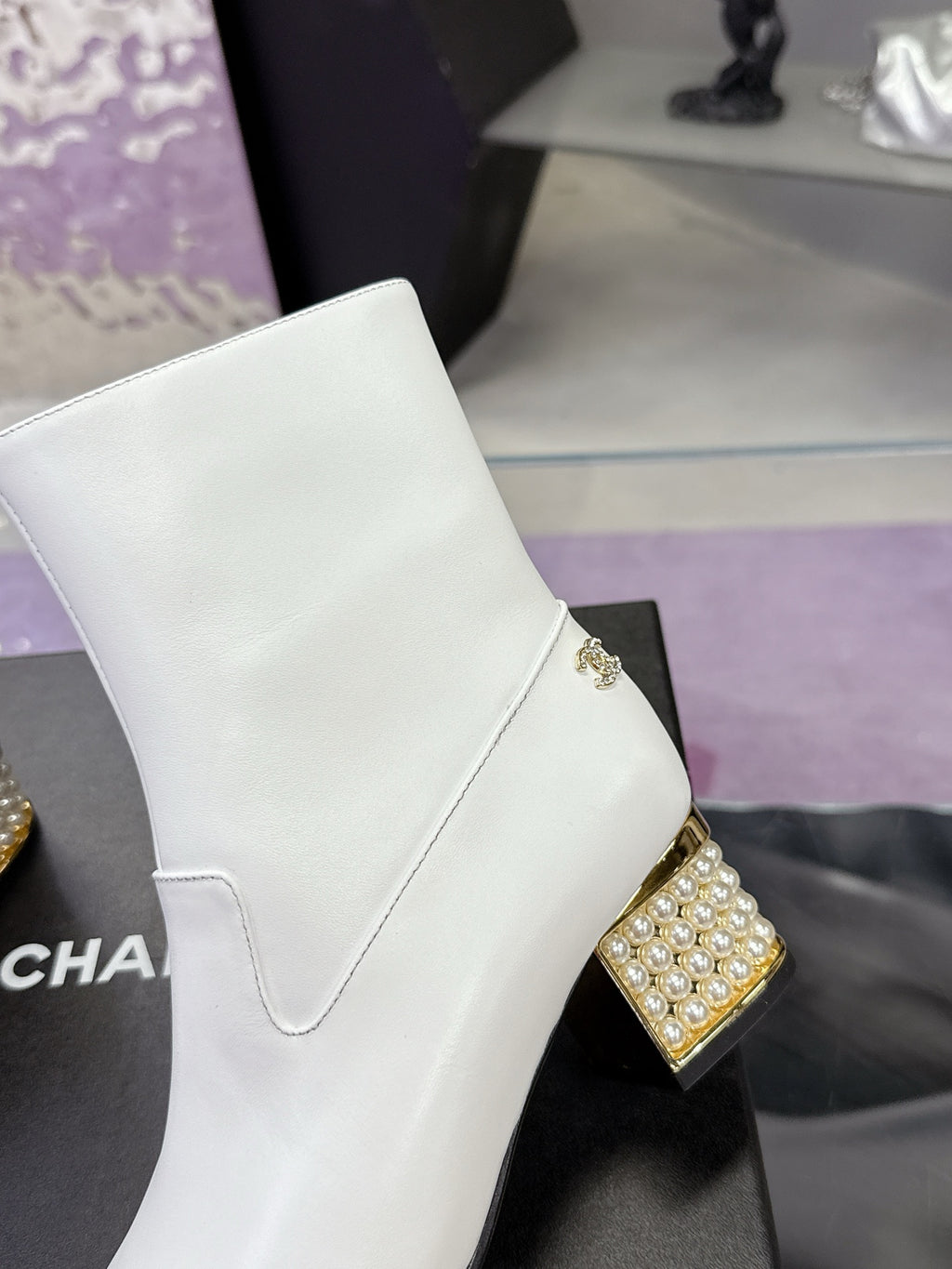 White mid-calf boot with gold jeweled heel and crest-style side charm