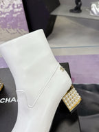 White mid-calf boot with gold jeweled heel and crest-style side charm
