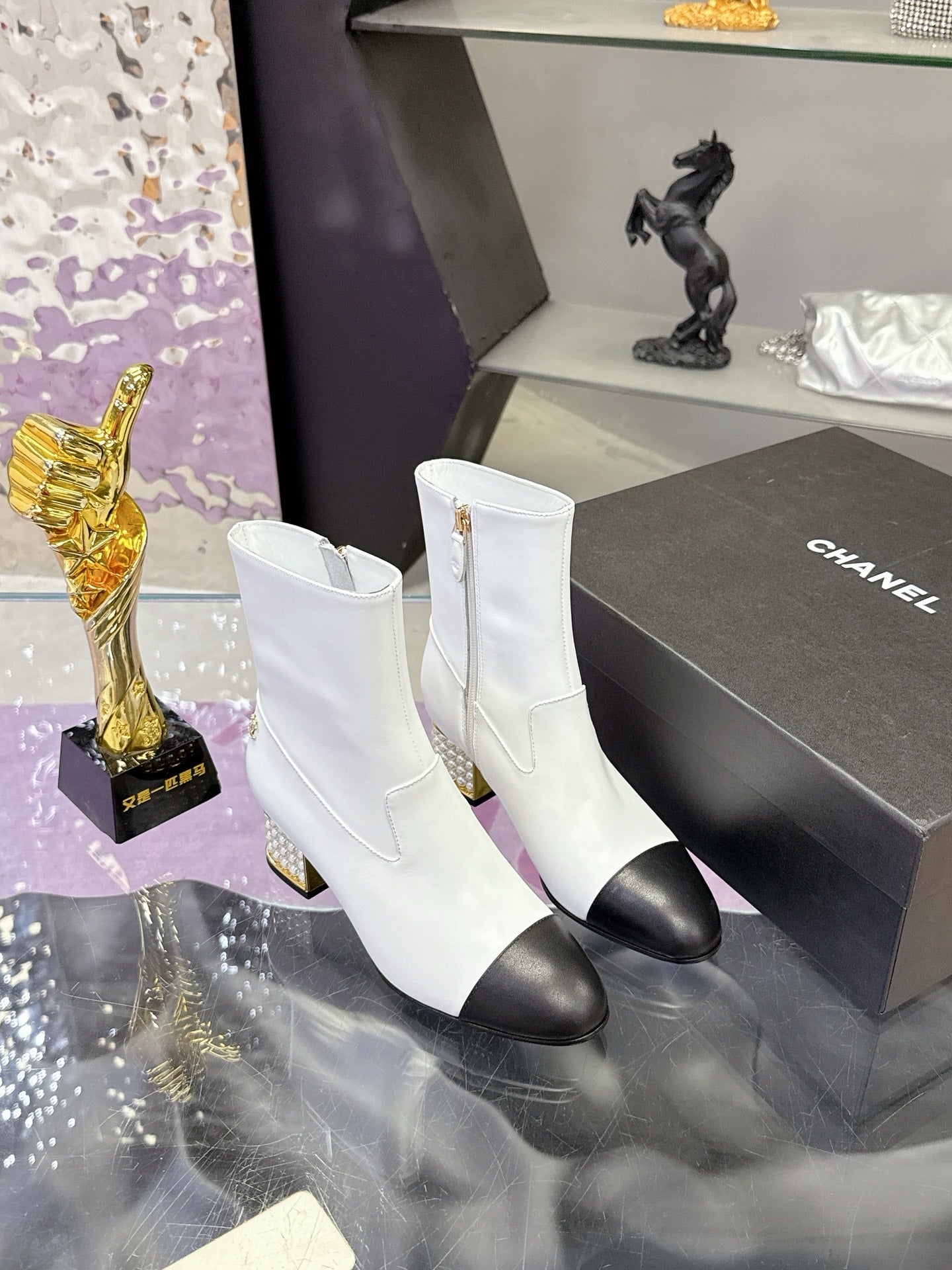 White mid-calf boots with gold zipper pull, black toe caps, and jeweled gold heels