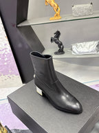 Black leather ankle boots with block heel and side emblem on gray box