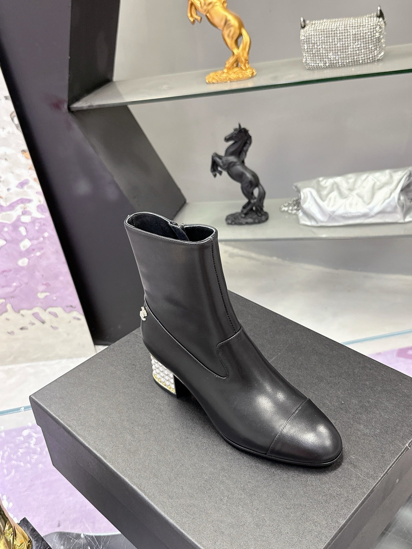 Black leather ankle boots with block heel and side emblem on gray box