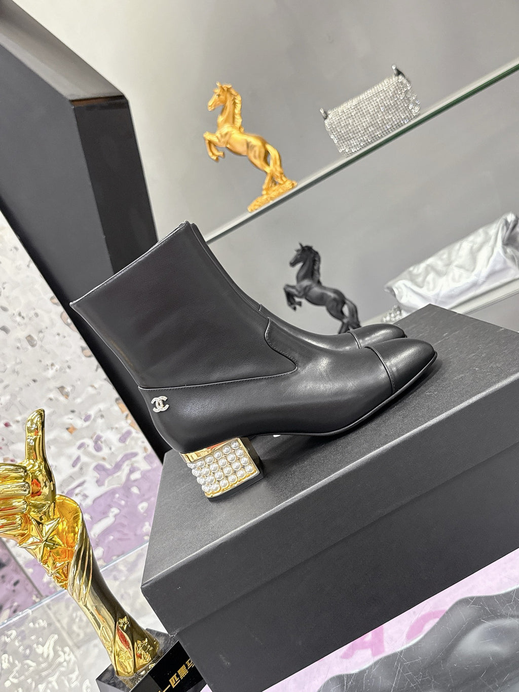 Black leather Chelsea-style ankle boots on gray box, low block heel