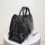 Balenciaga black leather tote bag shown from side with shoulder strap and round hardware