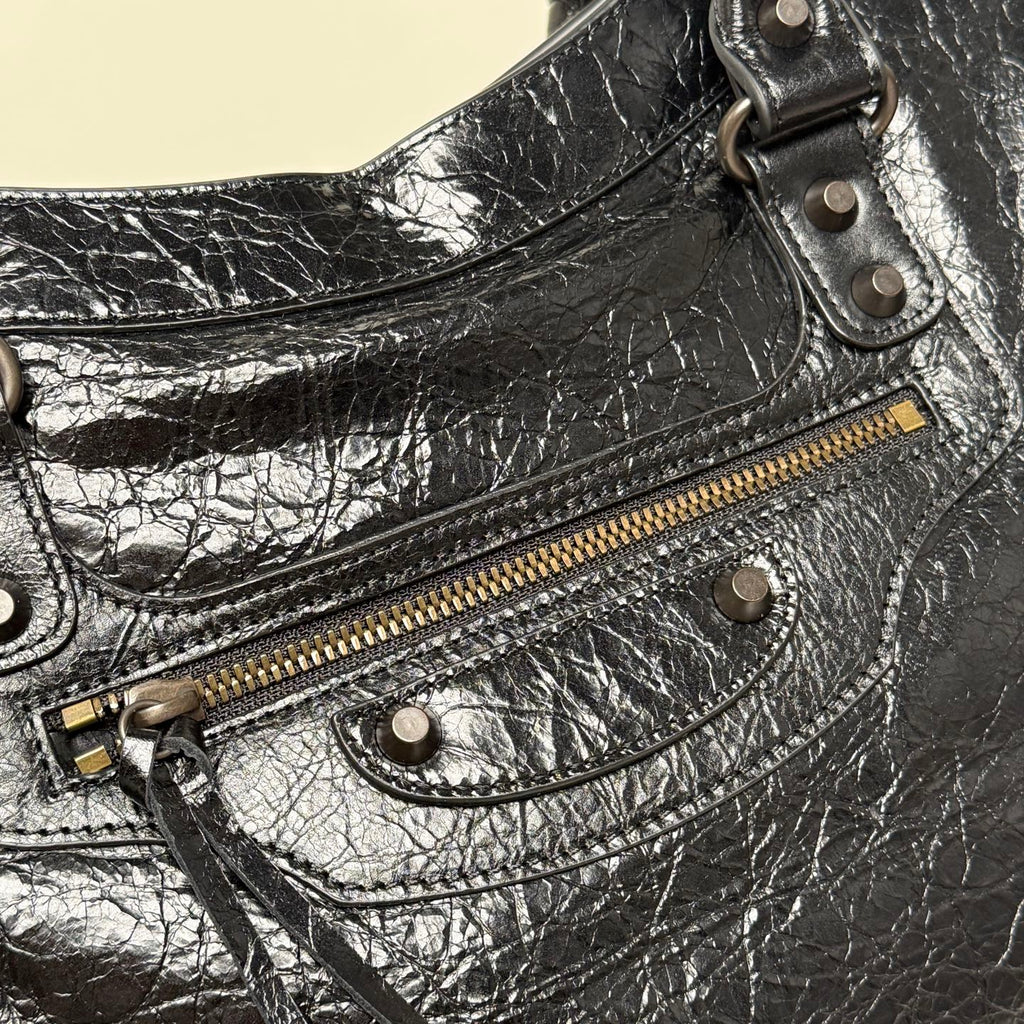 Balenciaga black leather bag close-up with zip pocket, metal eyelet straps