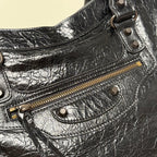 Balenciaga black leather bag close-up with zip pocket, metal eyelet straps