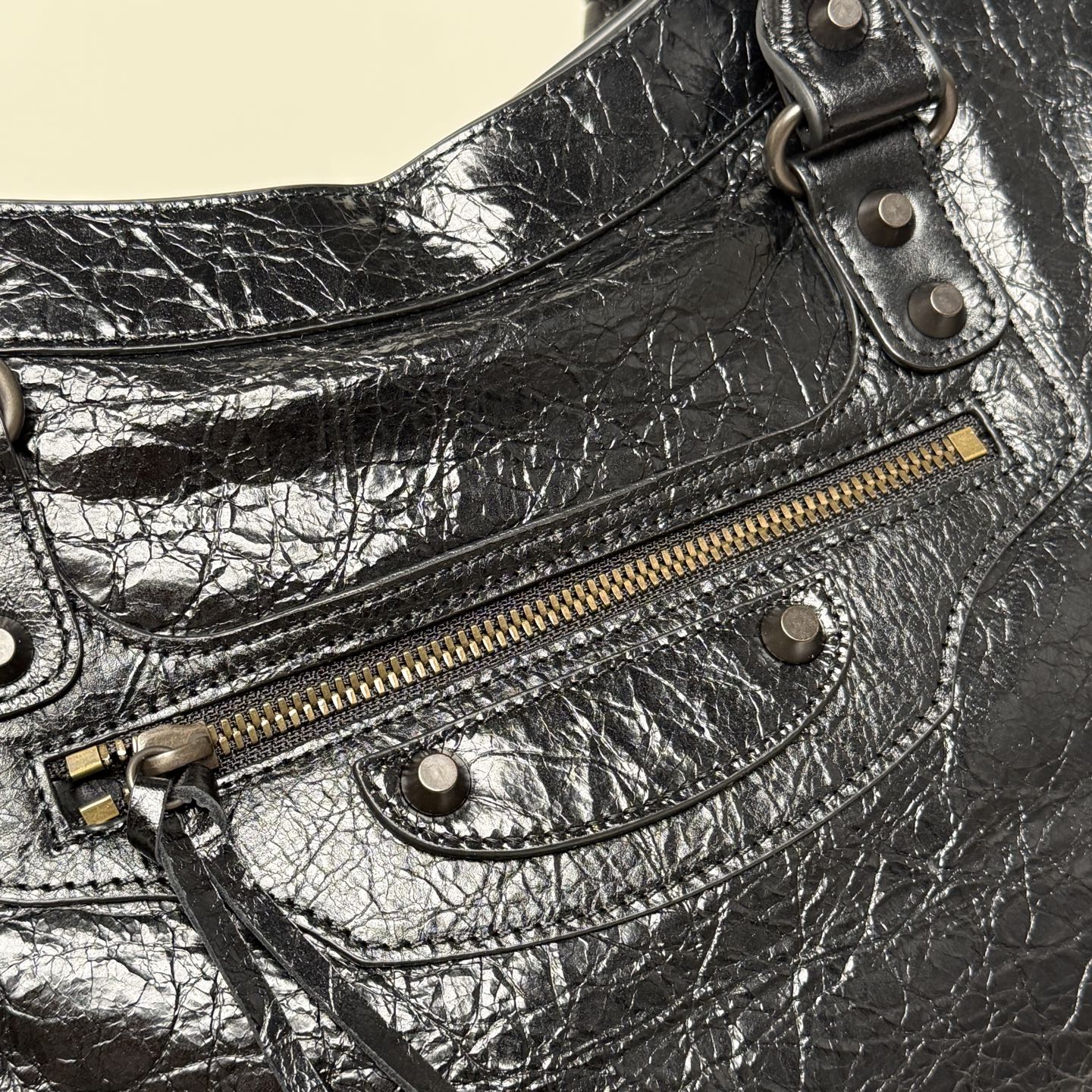 Balenciaga black leather bag close-up with zip pocket, metal eyelet straps
