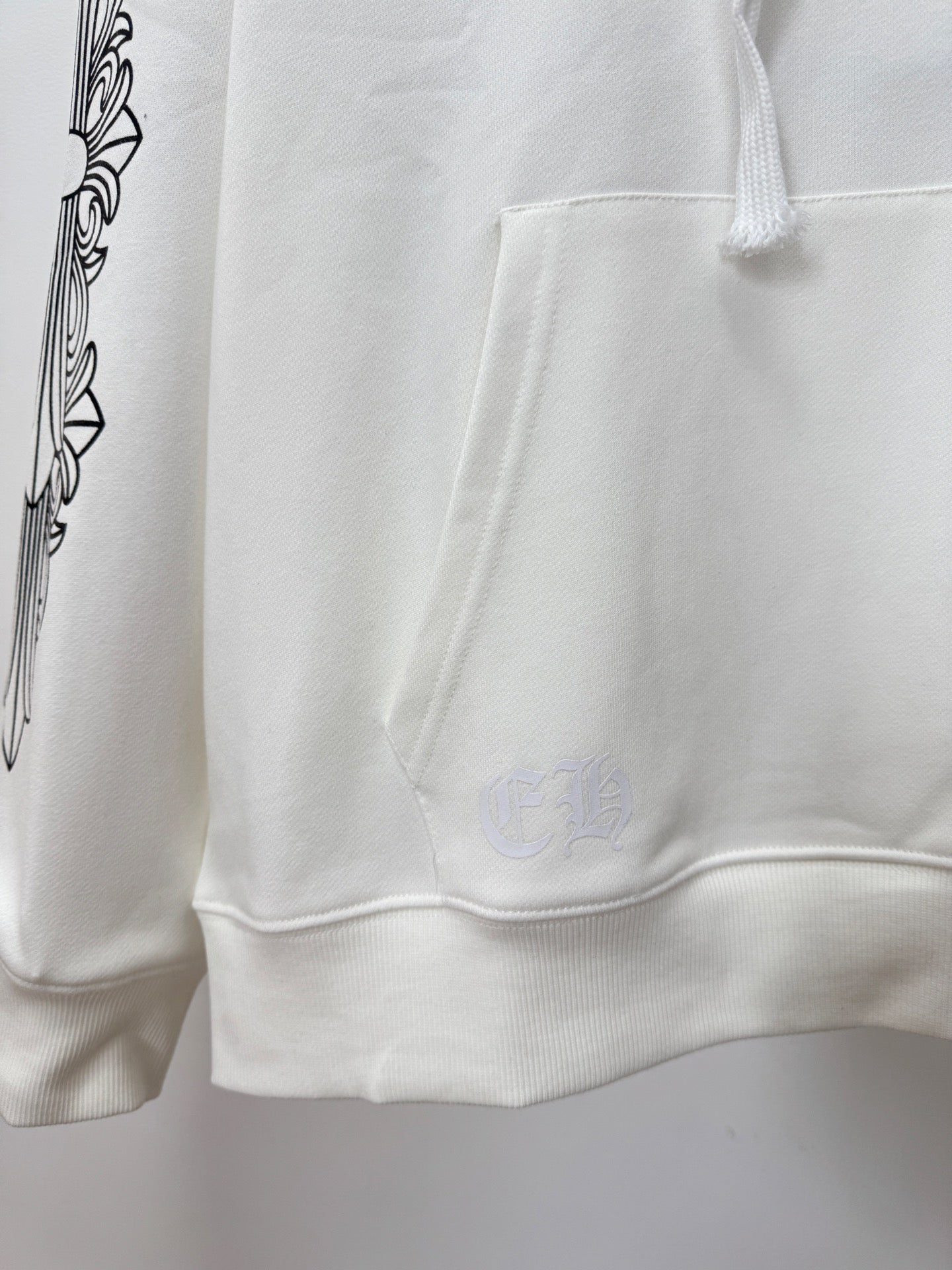 White hoodie cuffs and hem with small chest emblem near pocket
