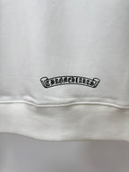 White hoodie close-up of small rectangular logo patch near hem