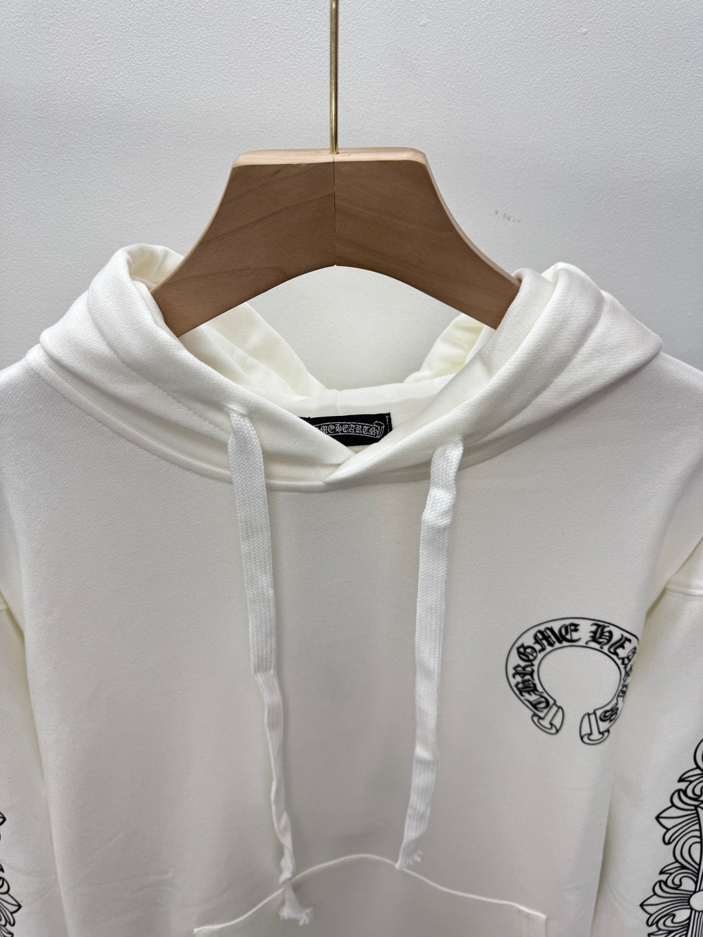 White hoodie with adjustable hood drawstrings; small chest logo graphic