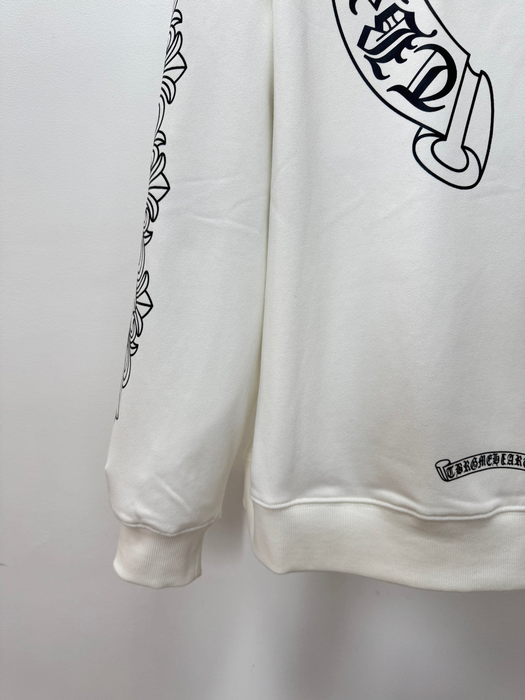 White hoodie side view with printed sleeve border and small logo near hem