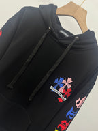 Black hoodie close-up with drawstring hood and colorful chest floral patch