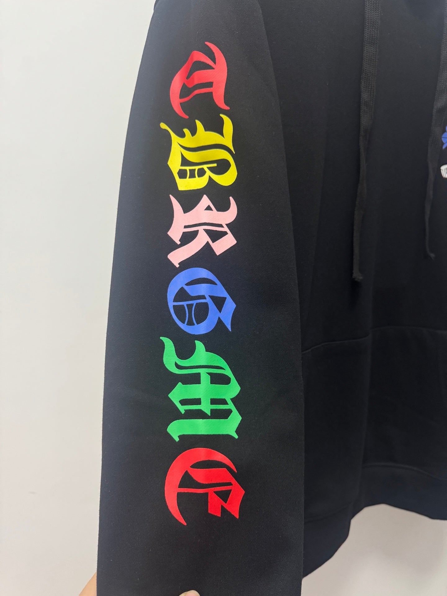 Black hoodie sleeve with colorful vertical letters graphic
