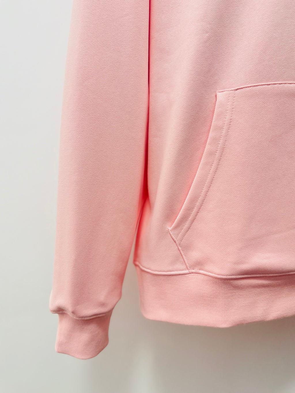 Pink hoodie front view showing drawstring-free kangaroo pocket and ribbed cuffs