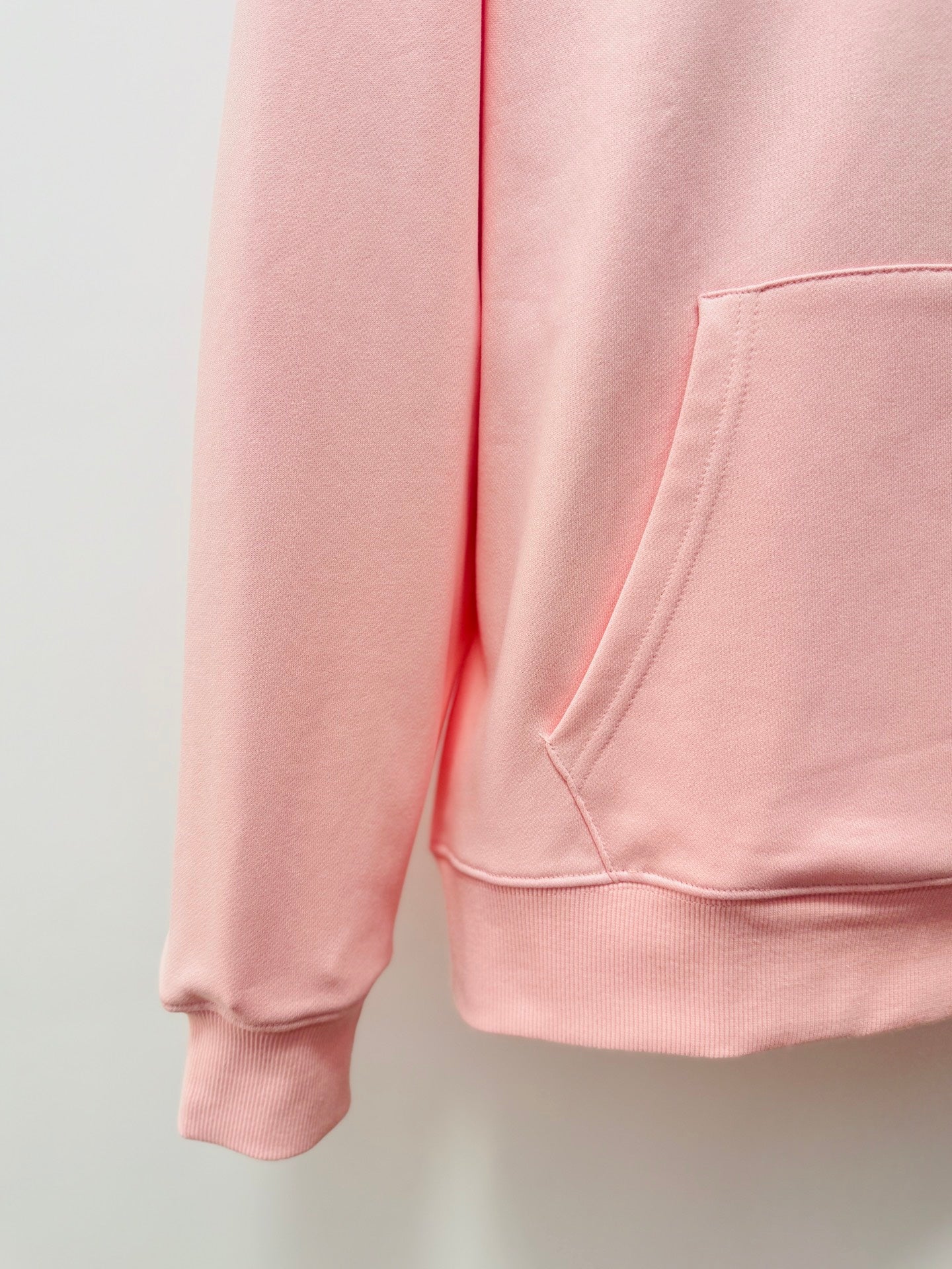 Pink hoodie front view showing drawstring-free kangaroo pocket and ribbed cuffs