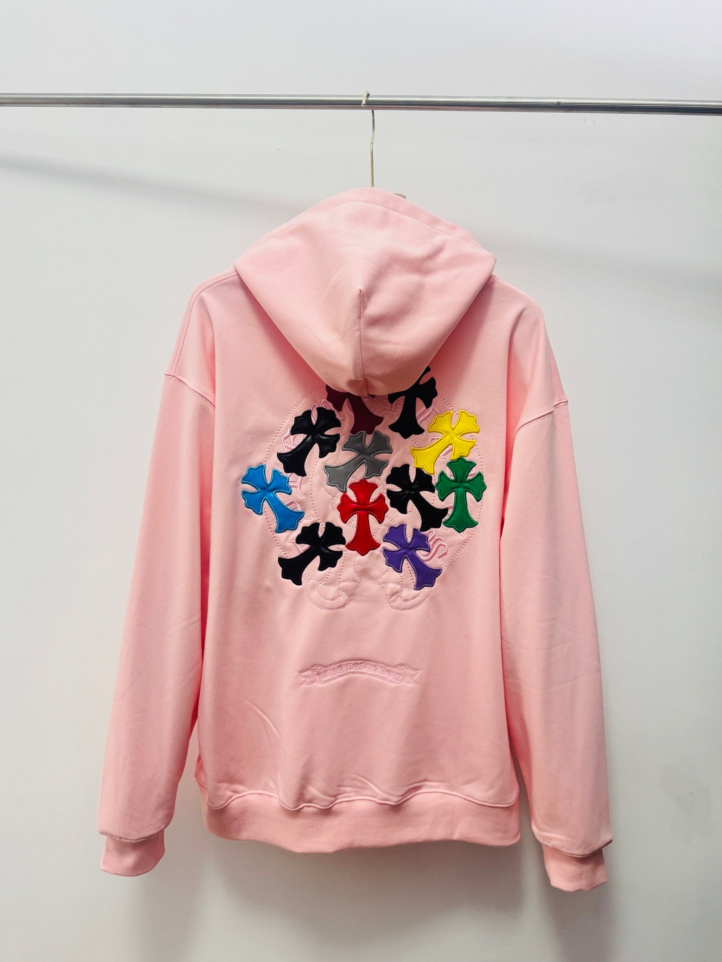 Pink pullover hoodie with hood, pouch pocket, and large multicolor floral back embroidery