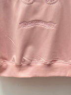 Light pink hoodie close-up of textured chest logo embroidery under the collar