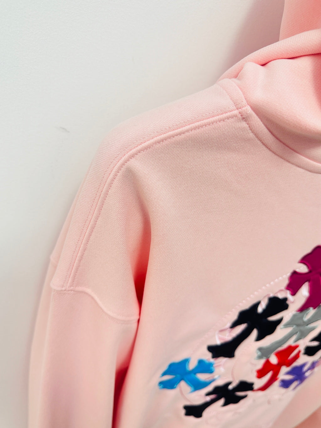 Pink hoodie sleeve and shoulder close-up with multicolor floral embroidery detail