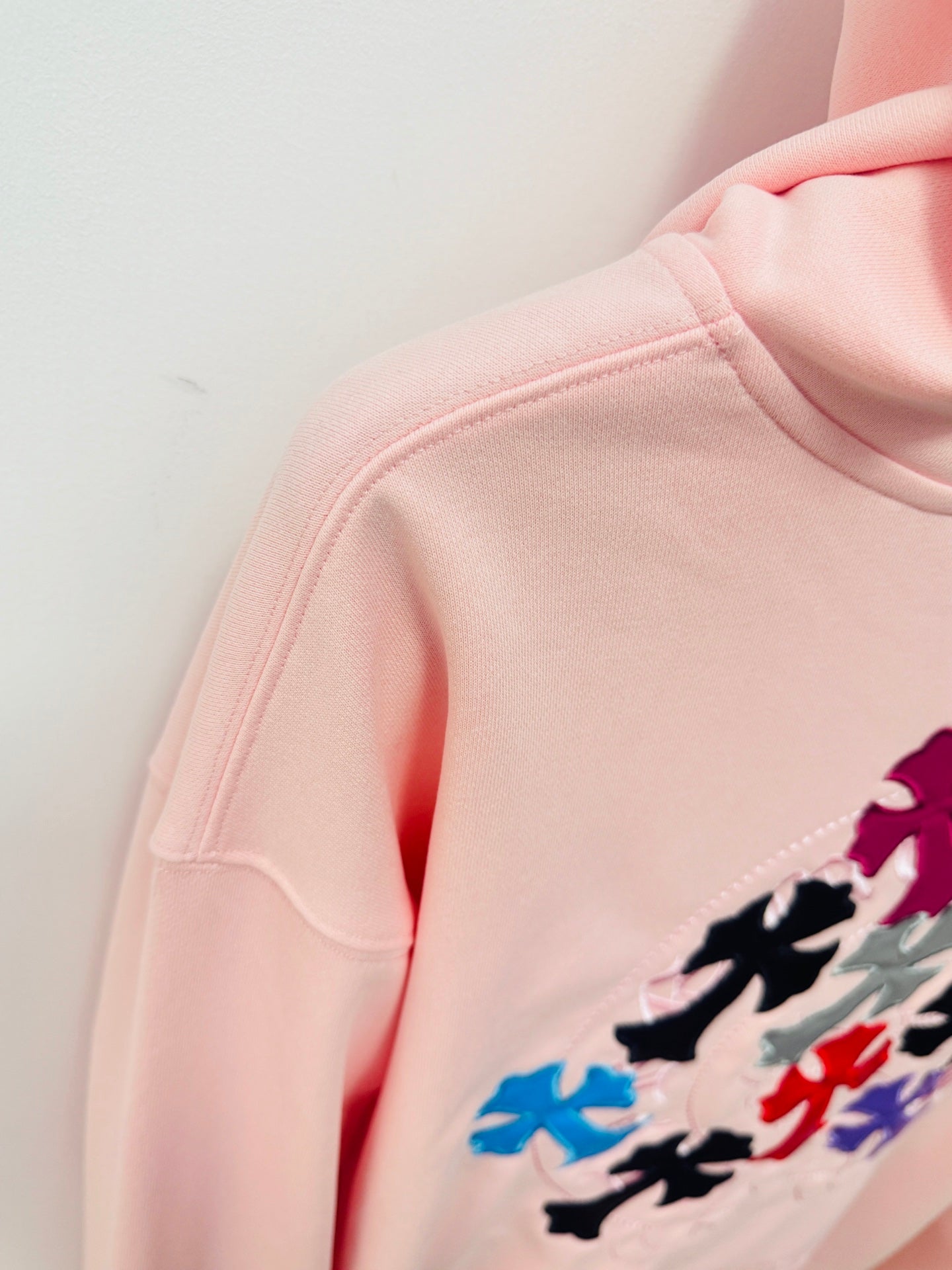 Pink hoodie sleeve and shoulder close-up with multicolor floral embroidery detail