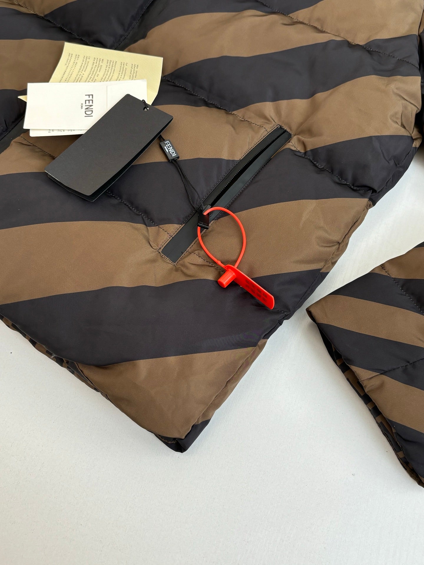 Fendi padded jacket laid flat with tag and red zipper pull