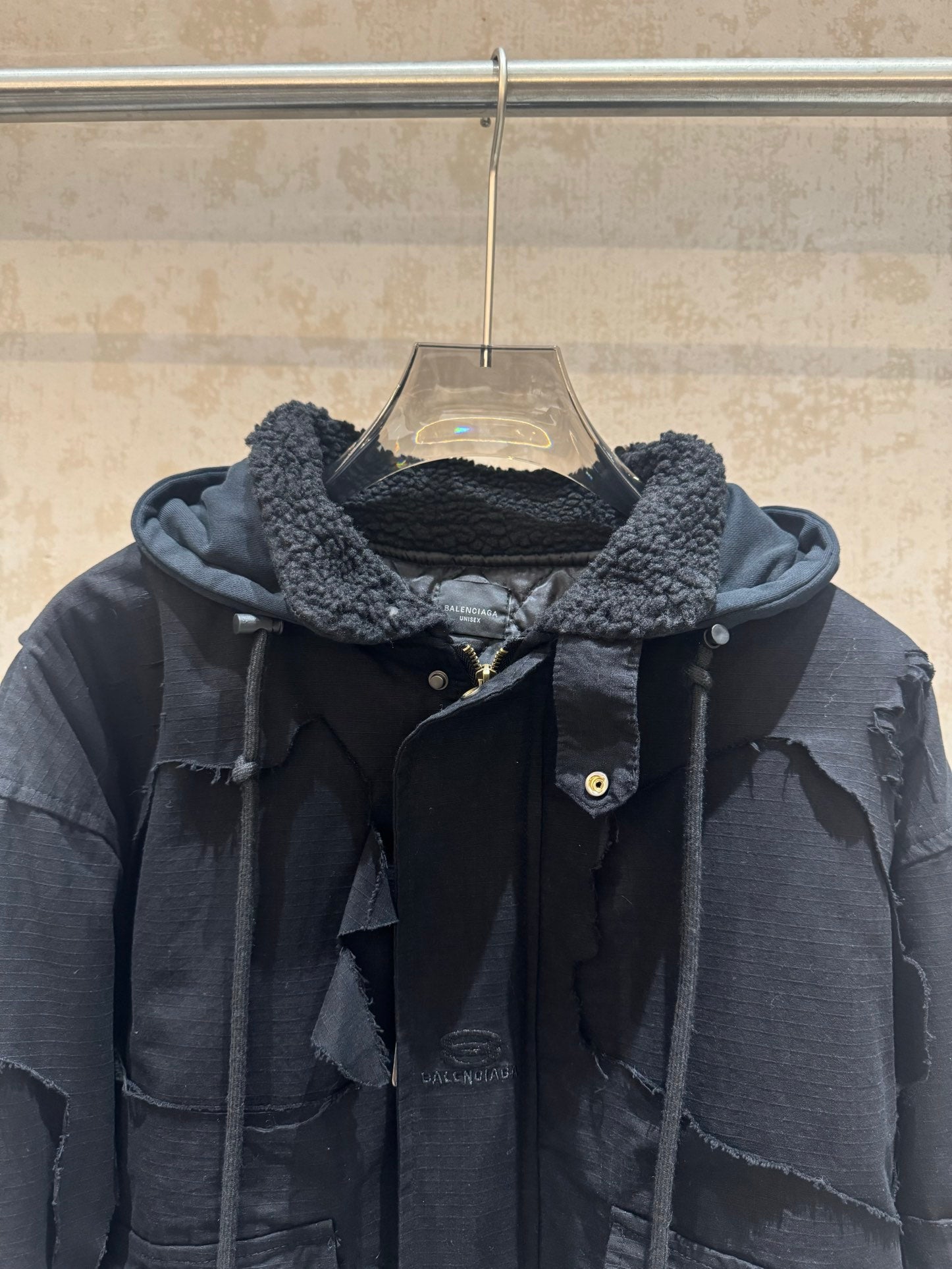 Balenciaga long hooded jacket close-up, dark with shearling-lined hood and snap buttons