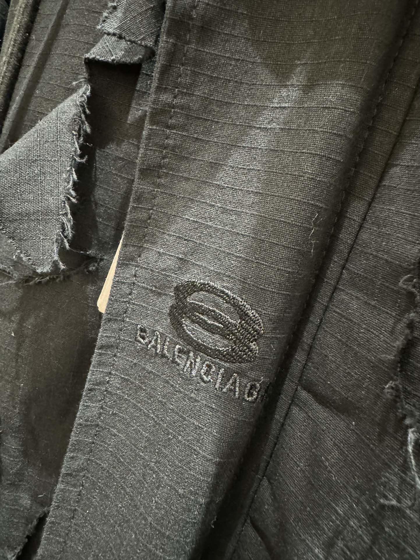Balenciaga logo patch on dark long jacket with distressed fabric and seams