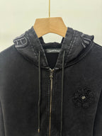 Dark zip-up hoodie close-up: hood, front zipper, drawstrings, and chest crest patch.
