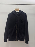 Dark zip-up hoodie with hood, drawstrings, front zipper, and small chest crest patch.