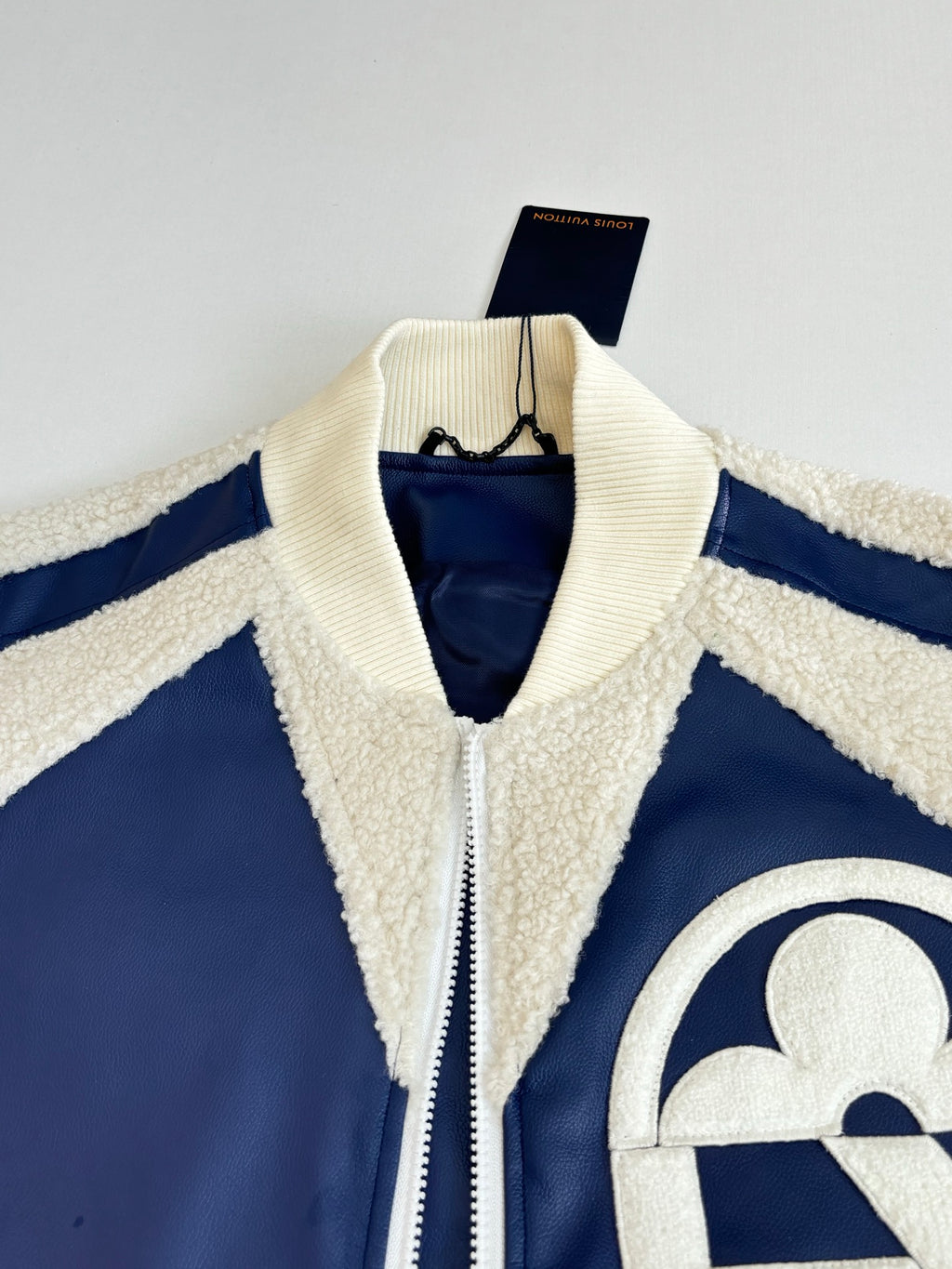 Sherpa-collared zip jacket with cream trim and partial logo patch detail on navy