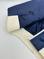 Side view of navy zip jacket with cream ribbed panel and sherpa-lined edge