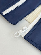 Close-up of navy jacket zipper track with cream sherpa trim and logo tab