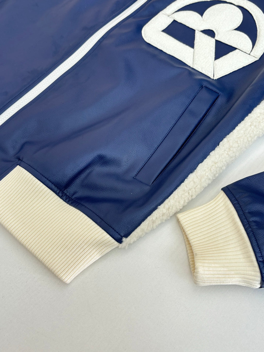 Close-up of navy jacket with cream ribbed cuffs and hem, sherpa-lined edges