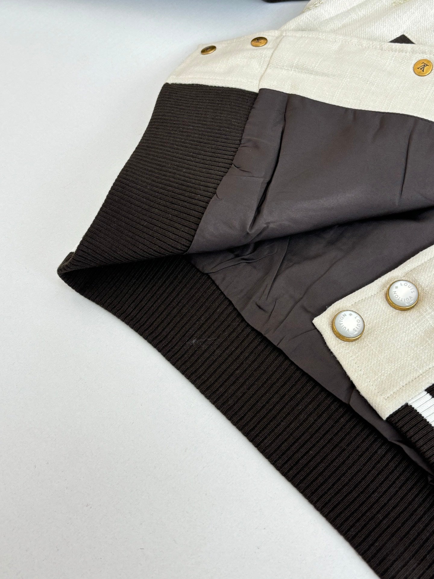 Louis Vuitton varsity jacket interior view, cream front band with black ribbed panel and snaps