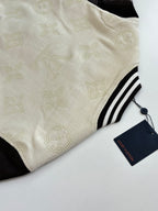 Louis Vuitton varsity jacket fabric close-up, cream textured knit with striped trim and tag