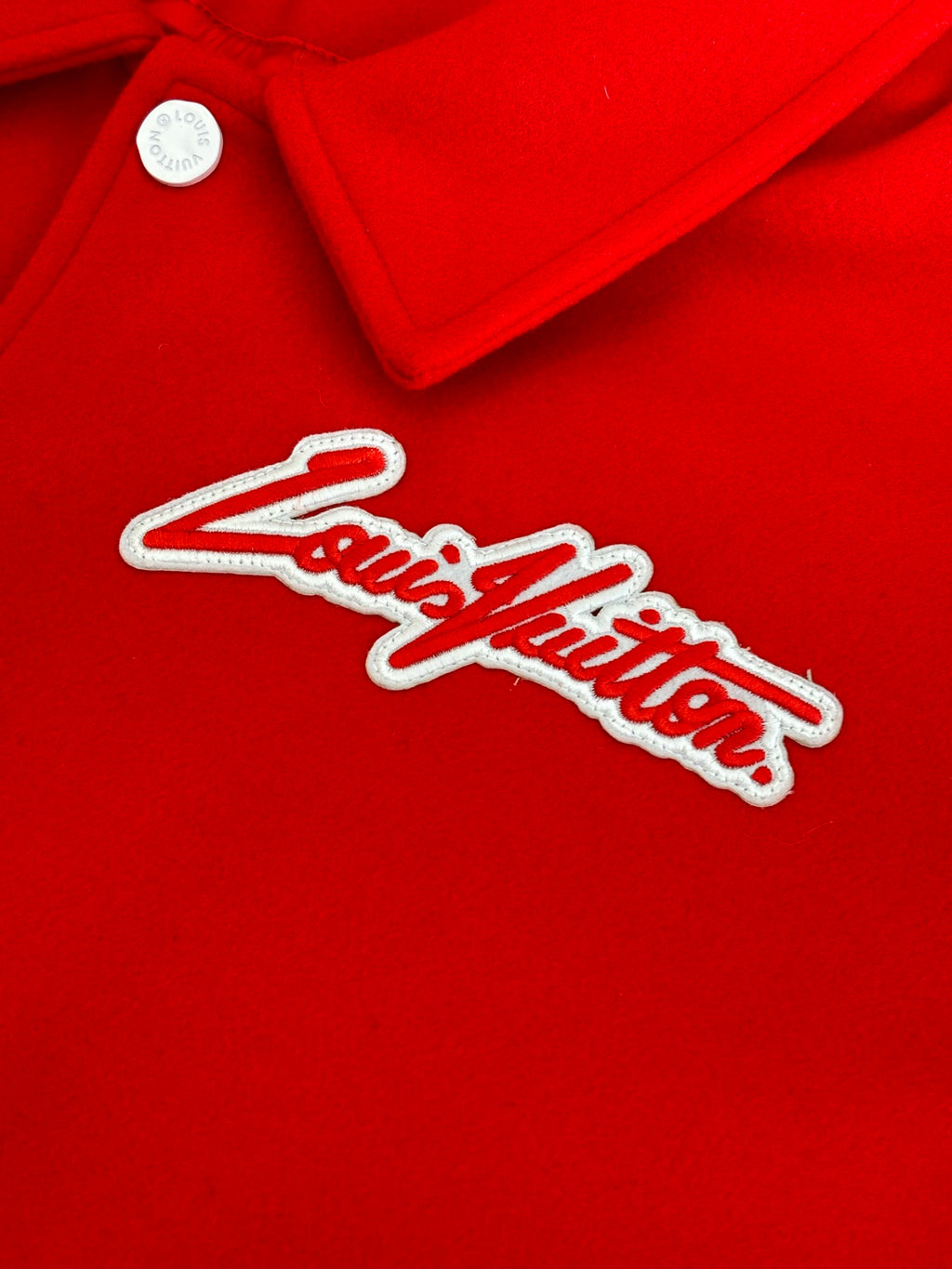 Louis Vuitton script logo on red varsity jacket with white outline