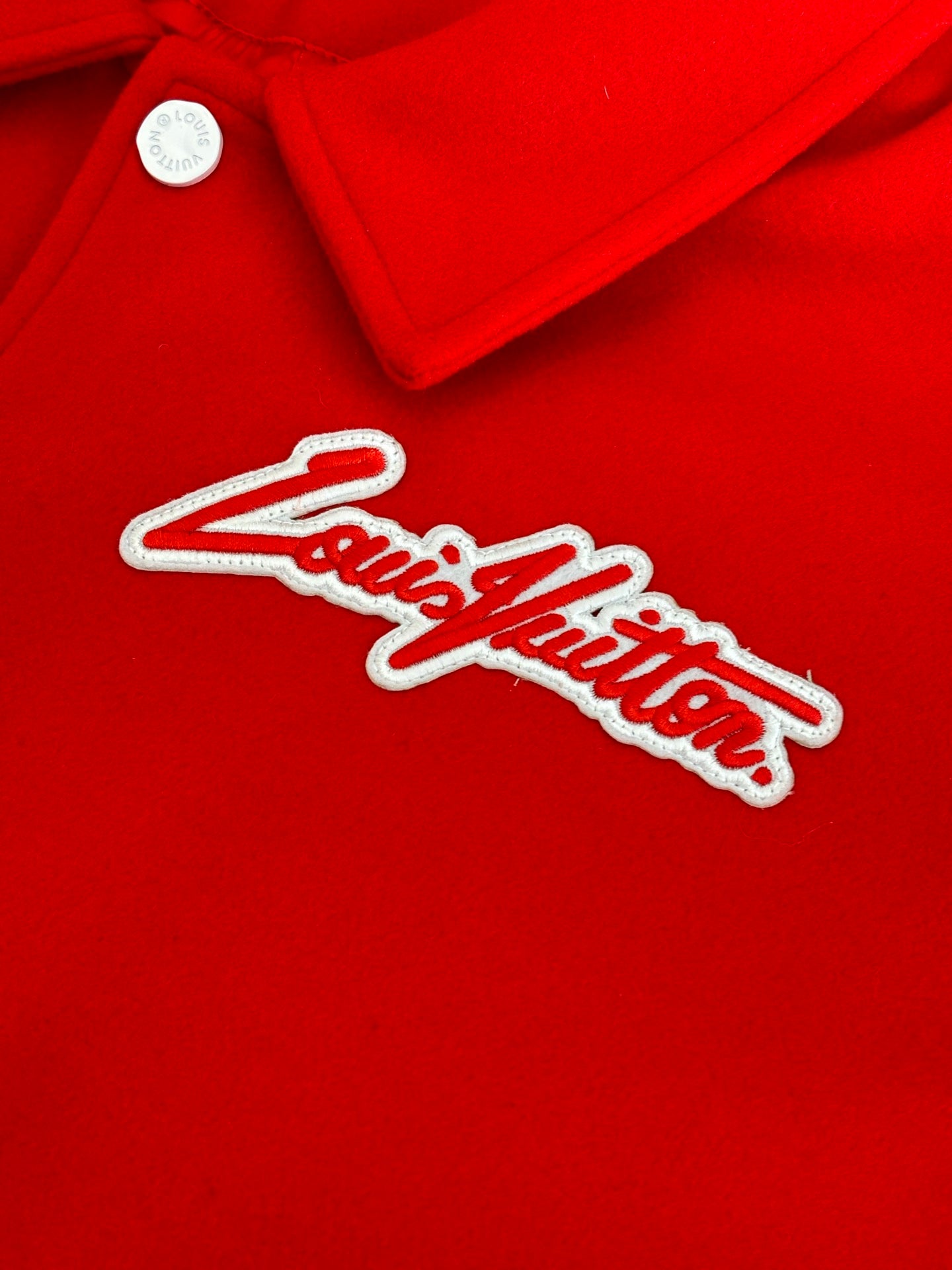 Louis Vuitton script logo on red varsity jacket with white outline