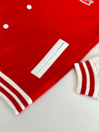 Red varsity jacket with white ribbed cuffs, sleeve pocket, and snap details
