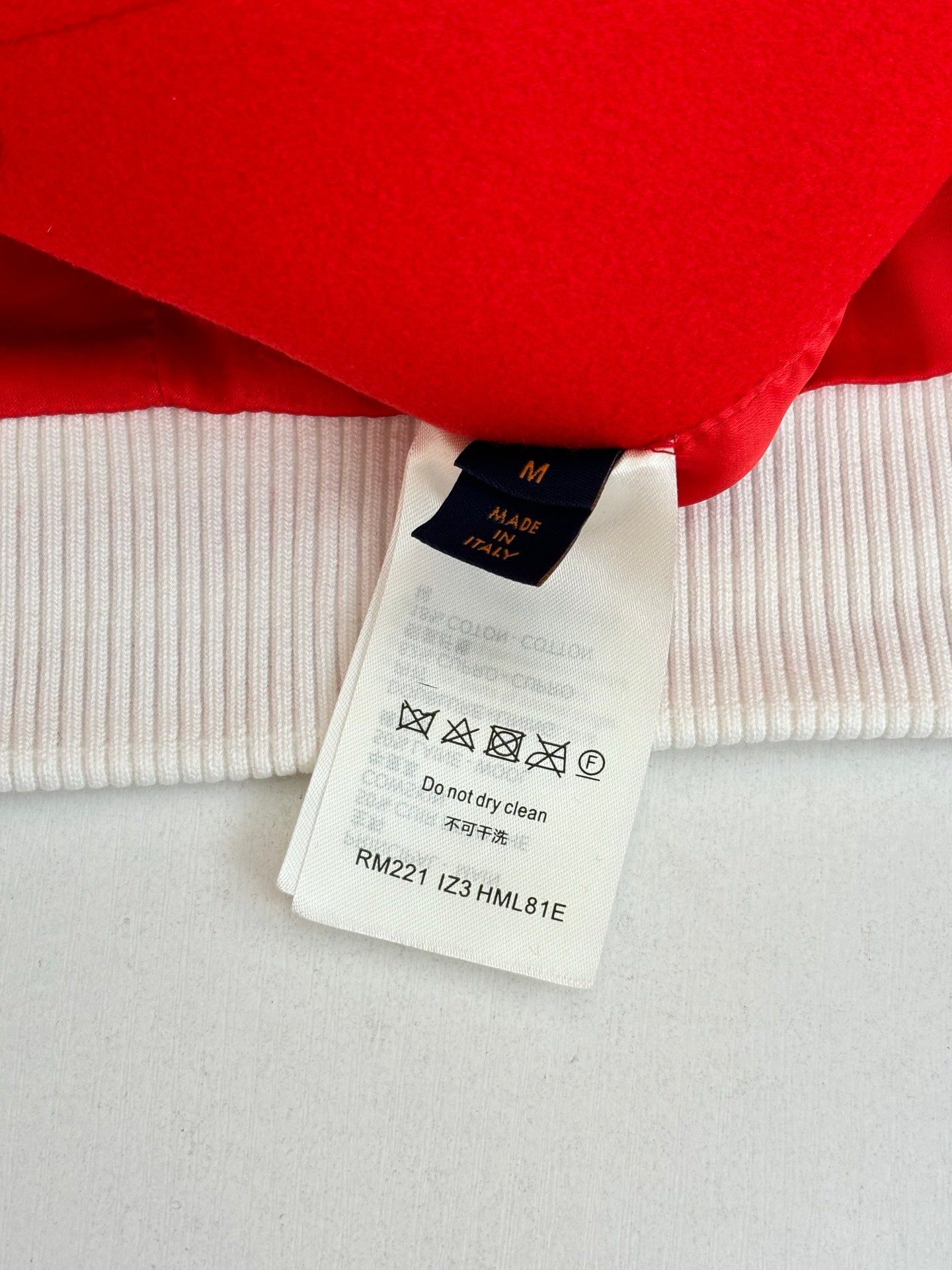 Long-sleeve top care label and white ribbed cuff under red hem