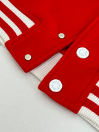 Red varsity jacket hem with white ribbed trim and round snap buttons